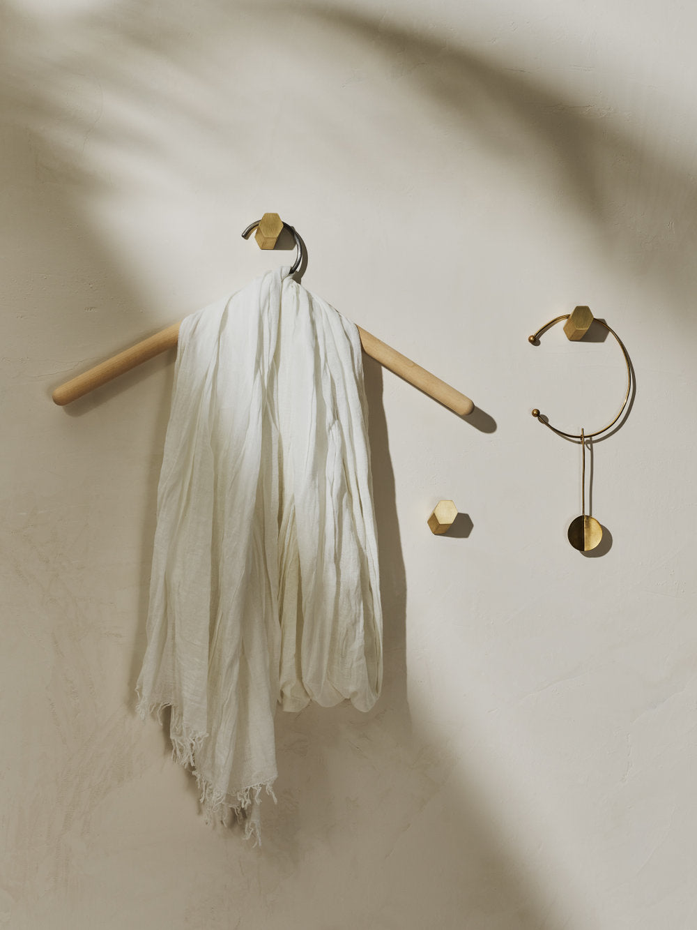 3 brass hexagonal wall hooks displaying clothes hanger and jewelry