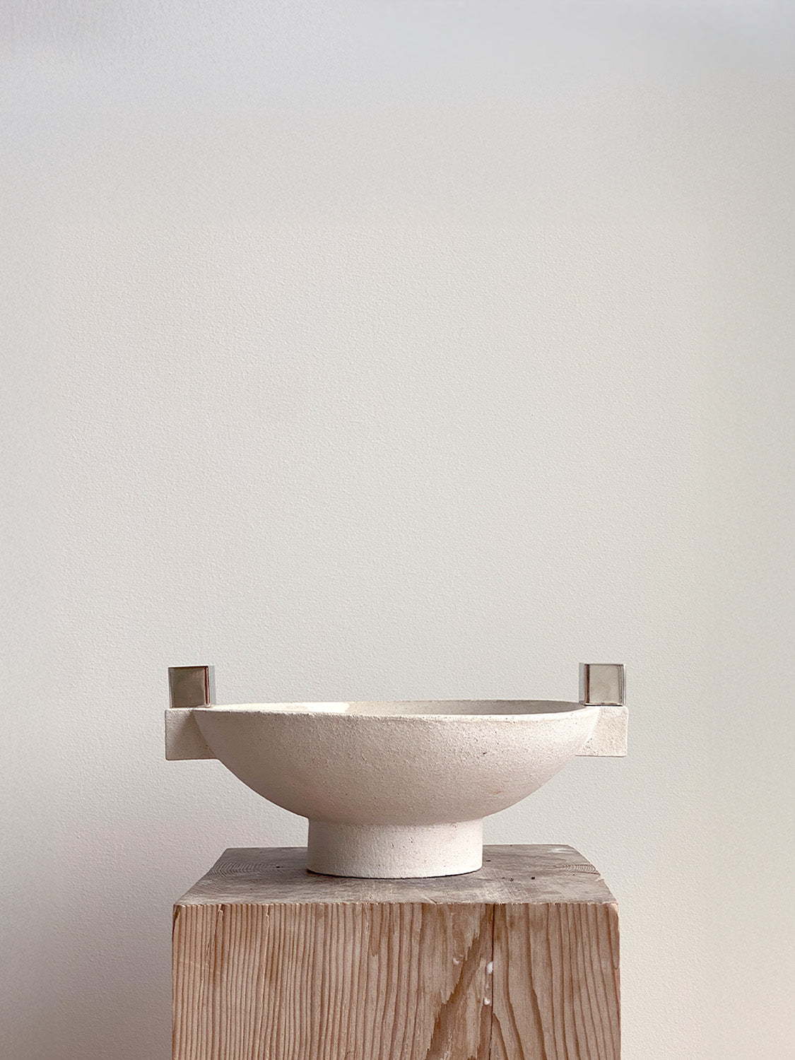 Ceramic bowl with handles on a wooden stand against a plain background