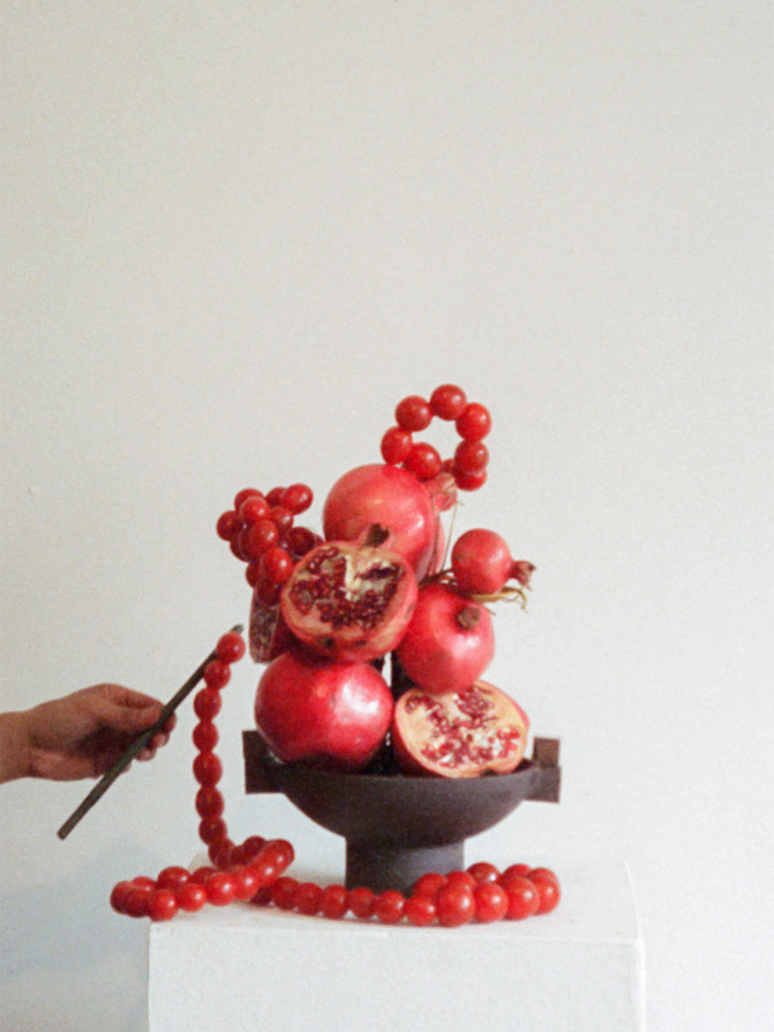 Decorative arrangement of pomegranates and red berries on a white background