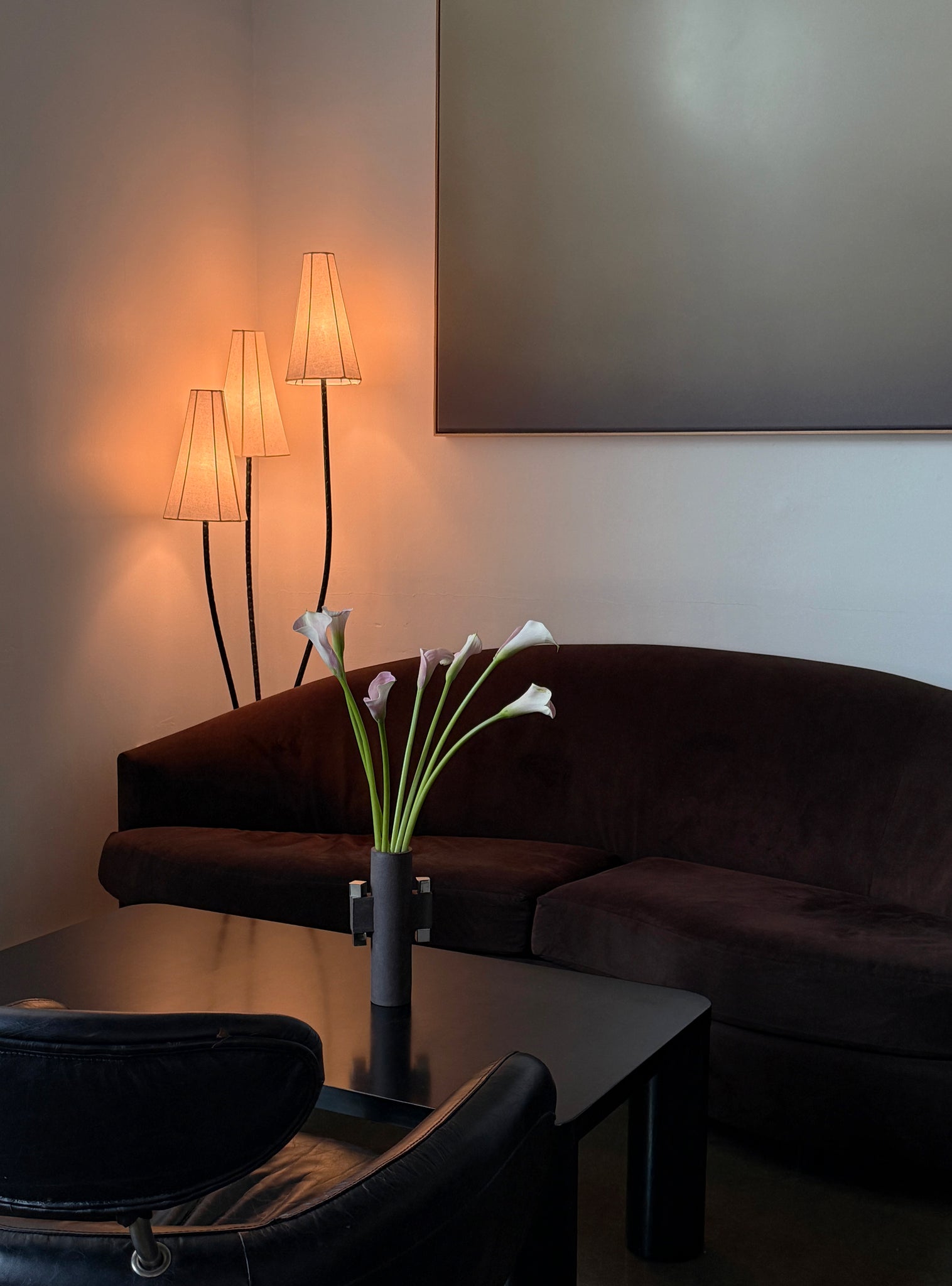 Modern living room with a brown sofa, table, and floor lamps.